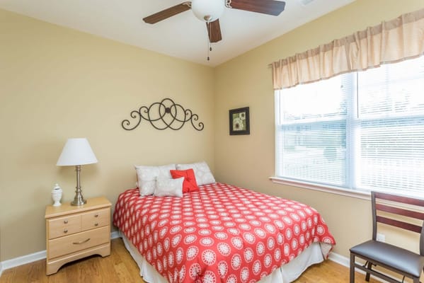 A cozy resident room with a red patterned bedspread