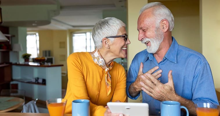 Senior couple laughing while using a tablet