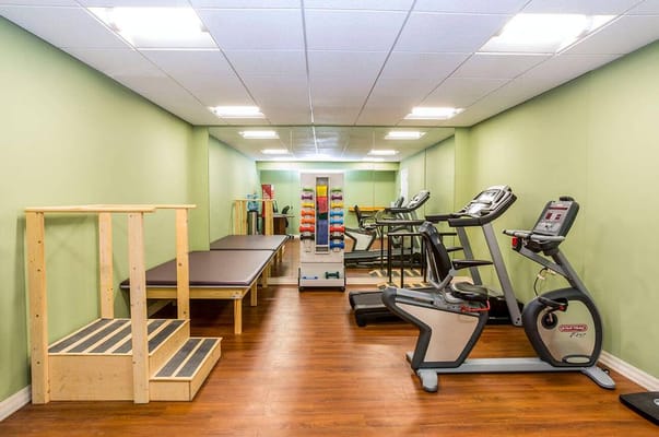 Well-equipped therapy room with exercise machines and therapy tables