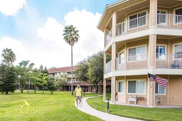 Two residents strolling along a path surrounded by greenery.