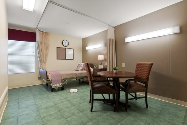 Comfortable nursing home resident room with a bed and dining area