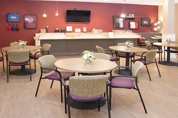 Cozy dining area with tables and chairs, decorated with flowers.