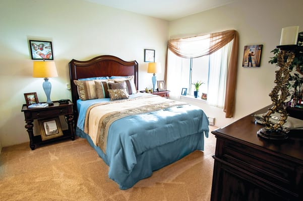 A well-furnished bedroom with a blue bedspread, bedside tables, and decorative elements.