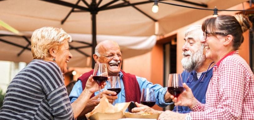 Seniors enjoying wine and laughter outdoors