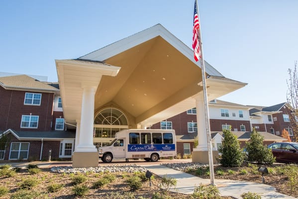 Front entrance of Capital Oaks Retirement Resort with a shuttle bus