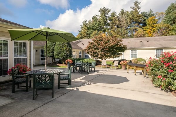 Outdoor seating area with tables and chairs under an umbrella.