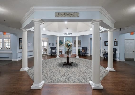 Bright lobby area with pillars and a round table featuring flowers