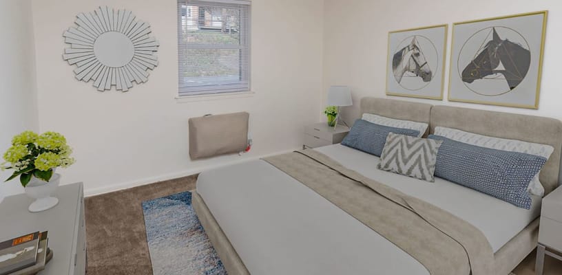 A well-furnished bedroom with a double bed, decorative pillows, and artwork.