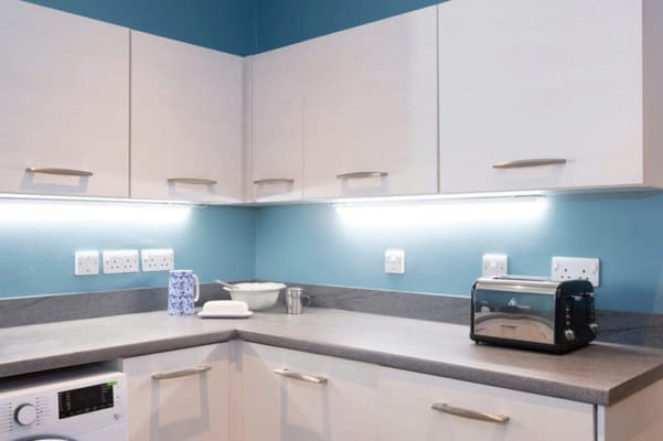 A modern kitchen with white cabinets and a blue wall.