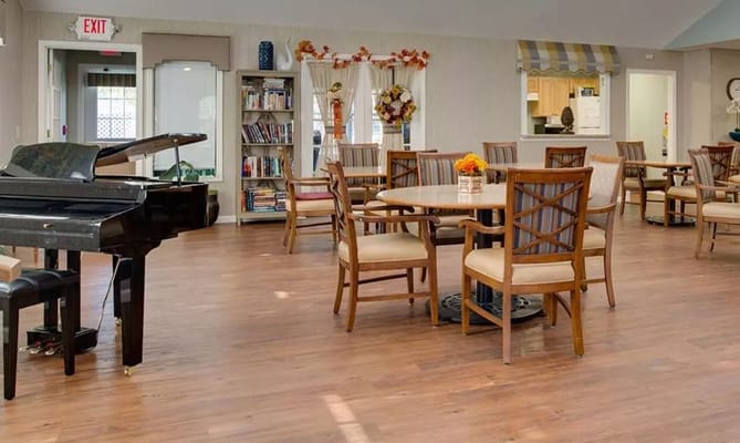 Spacious common area featuring a piano and dining tables.