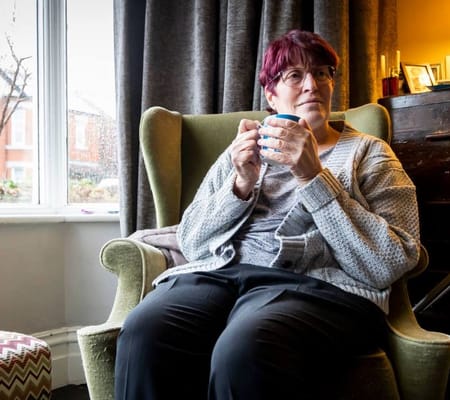Resident enjoying a warm drink in a cozy chair
