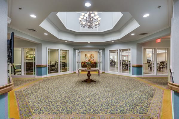 A spacious lobby with a chandelier and decorative floral arrangement at Chatham Ridge.