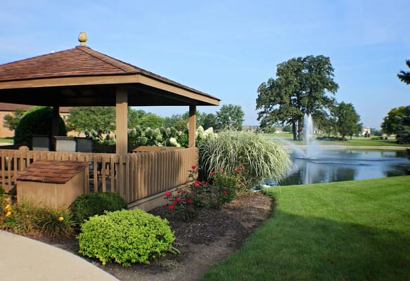 A gazebo by a pond with landscaped gardens