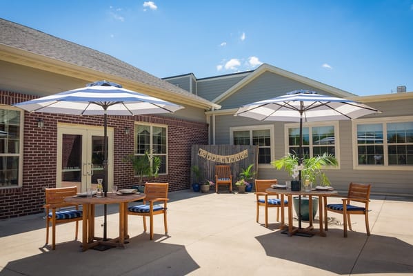 Outdoor area with tables and umbrellas in a senior living facility