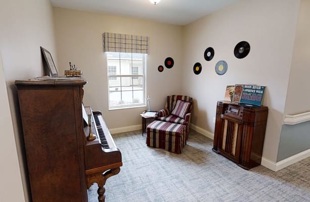 A cozy music room featuring a piano, striped chair, and vinyl records on the wall.