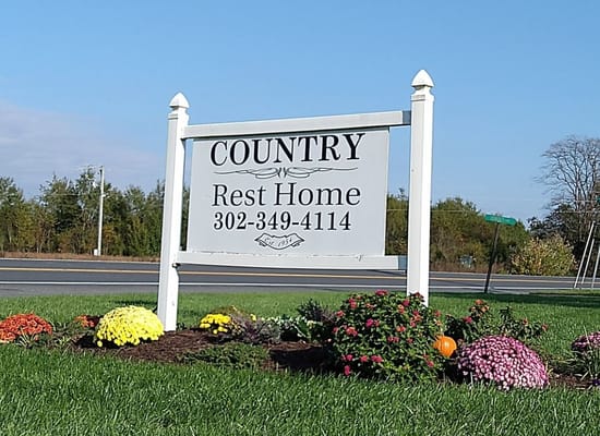 Sign for Country Rest Home surrounded by flowers