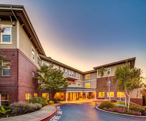 Entrance of a senior living facility surrounded by landscaping