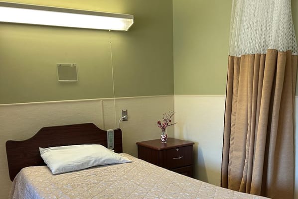 Interior of a private resident room with a bed and dresser