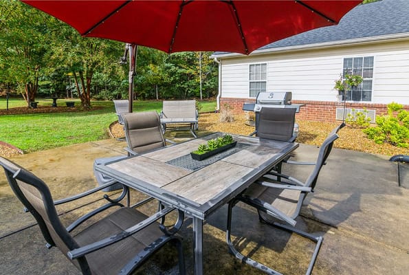 Outdoor dining area with a table and chairs under a red umbrella