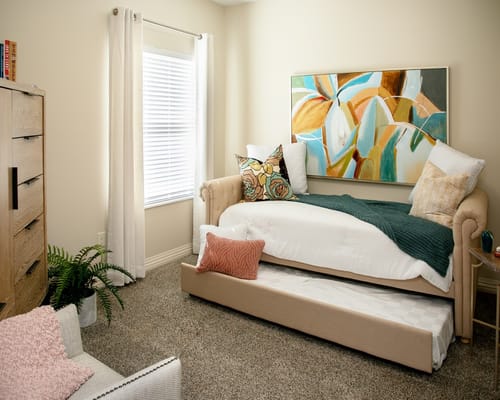 A well-decorated bedroom featuring a daybed, artwork, and natural light.