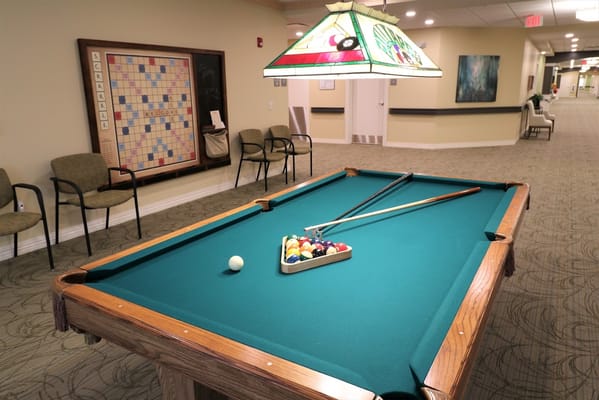 Billiard table in a common area with a large Scrabble board