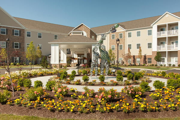 Colorful flower garden in front of Danbury Sanctuary Grande with a sculpture.
