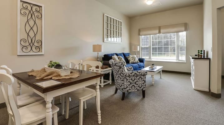 A cozy living room with a dining table, blue sofa, and patterned armchair.