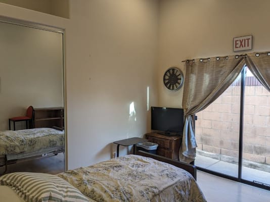Interior view of a cozy bedroom with a bed, TV, and exit door.