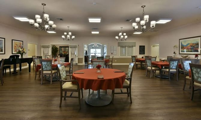 Warm and inviting dining room with orange tablecloths and chandeliers