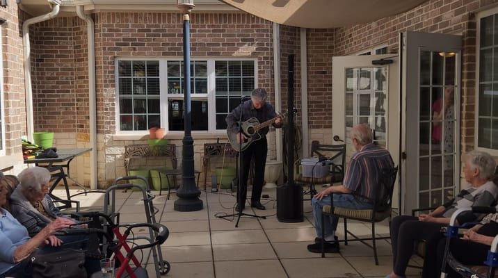 A musician performing on guitar for residents outside