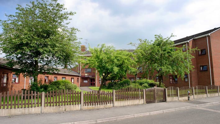 View of the exterior of Earls Lodge with trees and garden space.