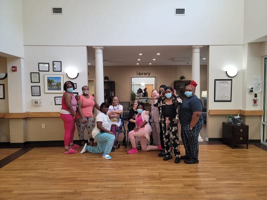 A group of residents posing together in the library area, all wearing masks.