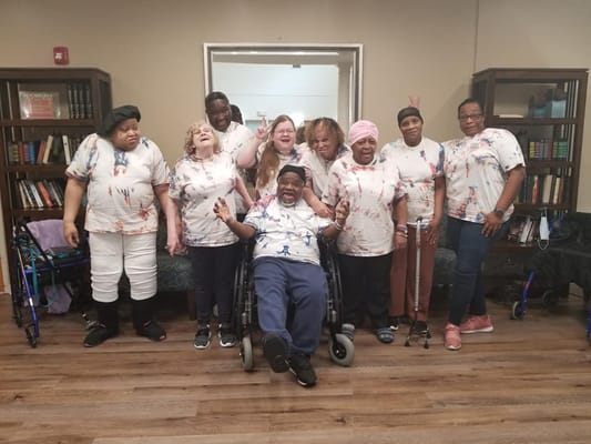 A group of nine residents participate in a creative activity, smiling and posing together.