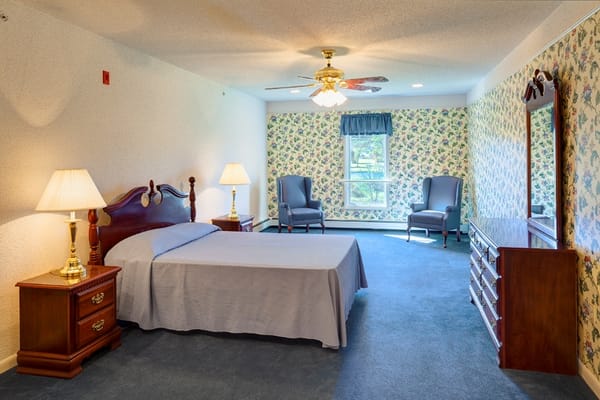 Brightly lit private resident room with floral wallpaper