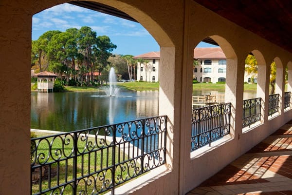 A view of a peaceful lake with a fountain, framed by an archway