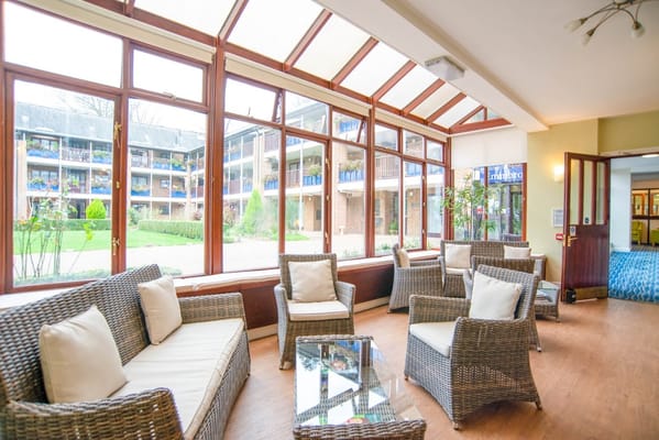 Sunlit common area with seating and view of gardens