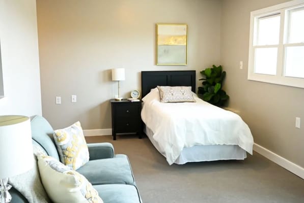 A well-furnished bedroom with a bed, side table, and a couch.
