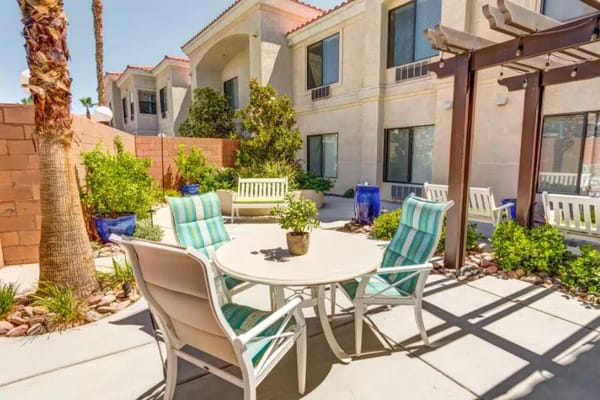 Outdoor seating area with tables and chairs surrounded by greenery.