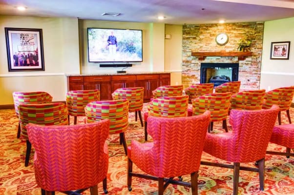Colorful chairs arranged in a community room with a TV.