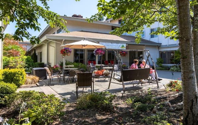 Two residents enjoying the outdoor patio with flowers and seating.
