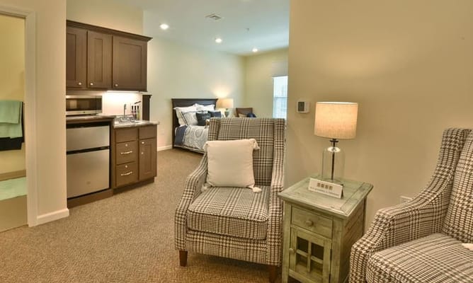 Interior view of a studio apartment featuring a kitchenette, seating area, and a bed.