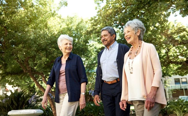 Three senior residents walking together in a garden