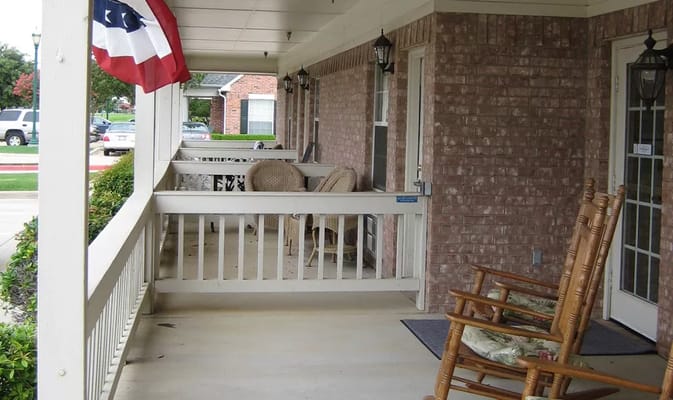 Covered porch area with chairs and flags