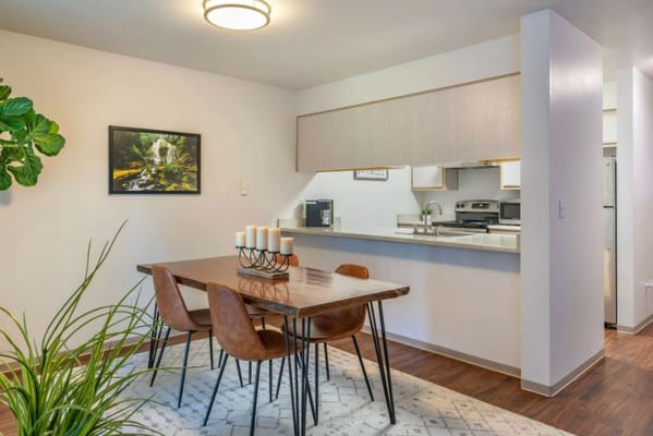 Cozy dining area with a wooden table and chairs next to a kitchen.