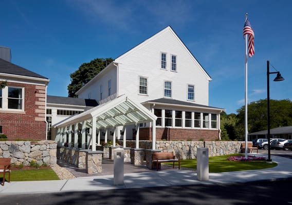 Main entrance of Forestdale Park Senior Living with glass canopy and American flag.