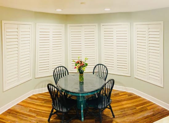 Table with four chairs and a vase of flowers in a room