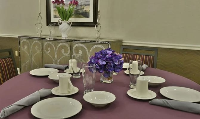 Set dining table with plates, glasses, and floral centerpiece.