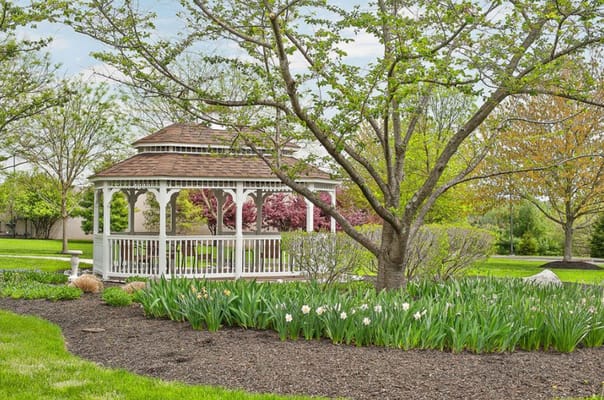 A gazebo surrounded by colorful flowers in a landscaped garden