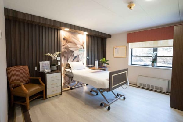Well-furnished patient room with a bed, chair, and window