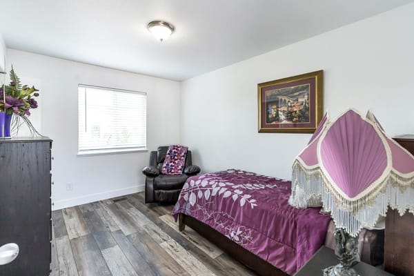 A well-furnished private resident room with a bed and chair